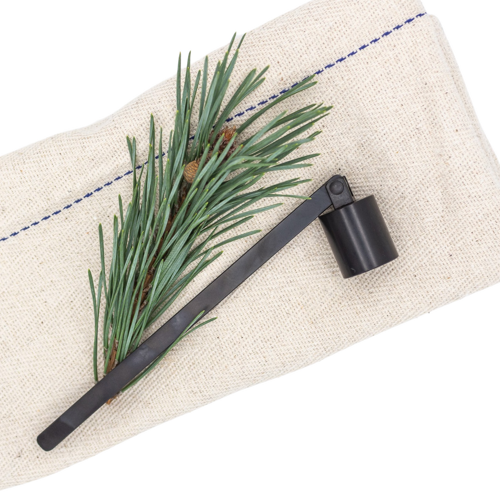 Black candle snuffer on linen tea towel